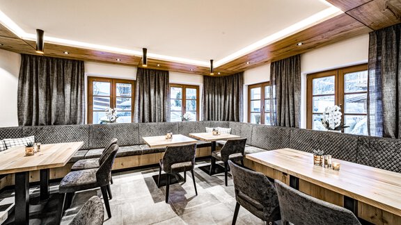 A stylish restaurant with wooden tables and comfortable chairs. The windows offer a view of the exterior and are decorated with elegant curtains. - Sonnalp Residences - Sölden