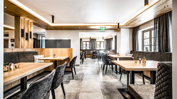 A modern restaurant with wooden-paneled walls and stylish seating. The atmosphere is bright and inviting. - Sonnalp Residences - Sölden