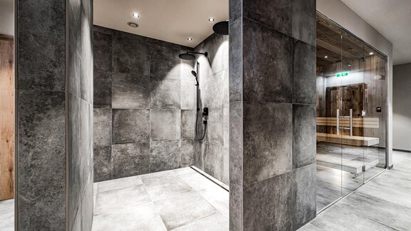 A modern shower with gray tiles and a clear glass wall. The space has a minimalist design and feels inviting. - Sonnalp Residences - Sölden
