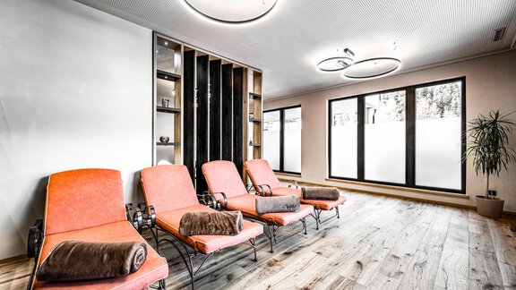 A modern relaxation room with orange loungers and a bright wooden floor. Large windows allow plenty of natural light in and create a peaceful atmosphere. - Sonnalp Residences - Sölden