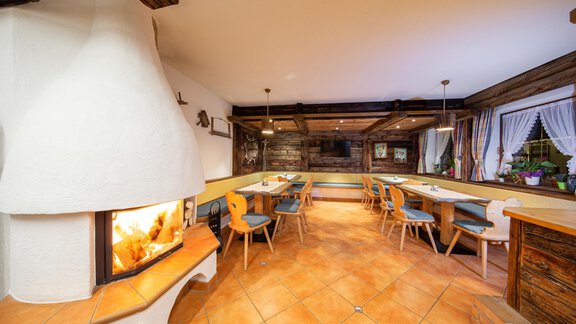 A cozy dining room with an open fireplace and wood decor. The tables and chairs invite for conversation. - Toni's Ferienheim - Sölden
