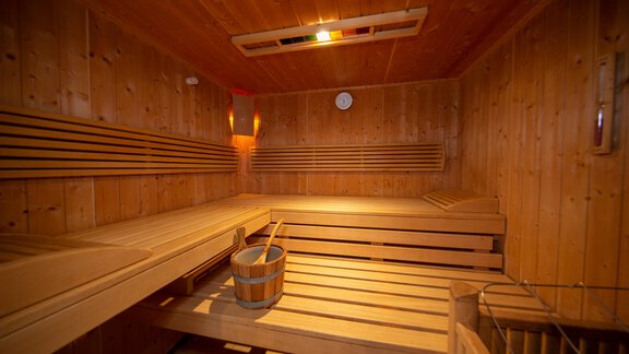 A cozy sauna with wooden paneling. In the middle, there are benches and a bucket with a ladle. - Toni's Ferienheim - Sölden