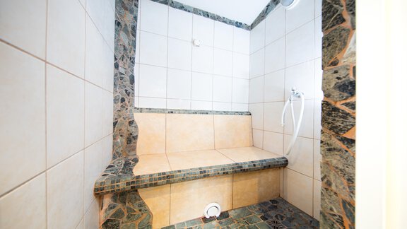 A clean shower with a tiled bench. The walls are decorated with light and dark tiles. - Toni's Ferienheim - Sölden