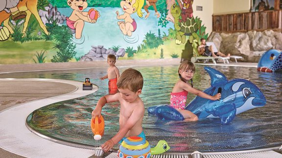 A swimming pool with colorful murals and three children playing with toys in the water. The atmosphere is cheerful and child-friendly. - Top Apart Daniela - Sölden