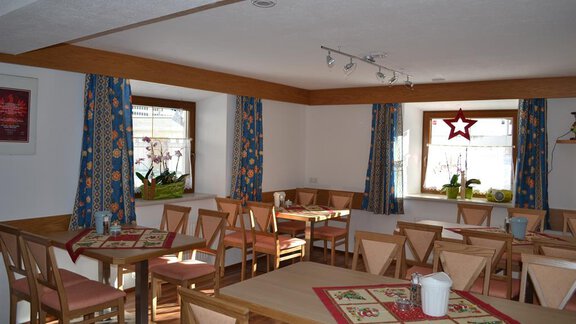 A cozy room with wooden chairs and tables. The walls are adorned with colorful curtains and decorations. - Appt. Garni Anny - Vent
