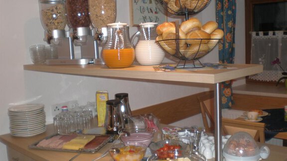 A breakfast buffet with various rolls, muesli, and fresh juices. The table is also set with ham, cheese, and fruits. - Appt. Garni Anny - Vent
