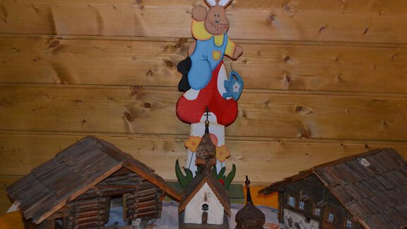 A colorful Easter decoration with an upright rabbit and several small wooden houses. The scene conveys a festive atmosphere. - Appt. Garni Anny - Vent