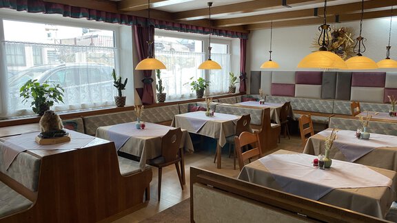 A cozy restaurant with wooden paneling and warm light. The tables are neatly set, and plants create an inviting atmosphere. - Gästehaus Edelweiss - Vent