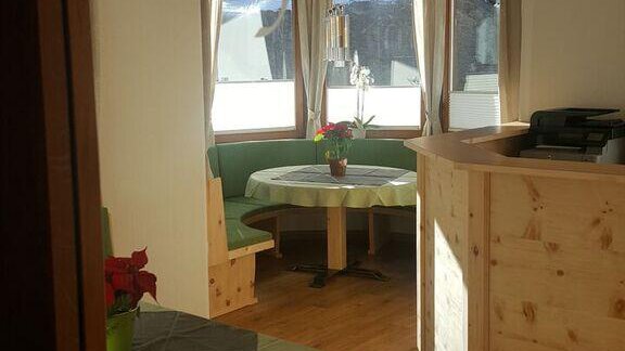 A cozy dining room with wooden furniture and tables. The large window front provides plenty of light and an inviting atmosphere. - Gästehaus Soldanella - Vent