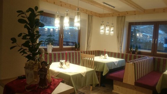 A cozy restaurant with wooden decor and warm lighting. The tables are clean and attractively set, surrounded by large windows. - Gästehaus Soldanella - Vent