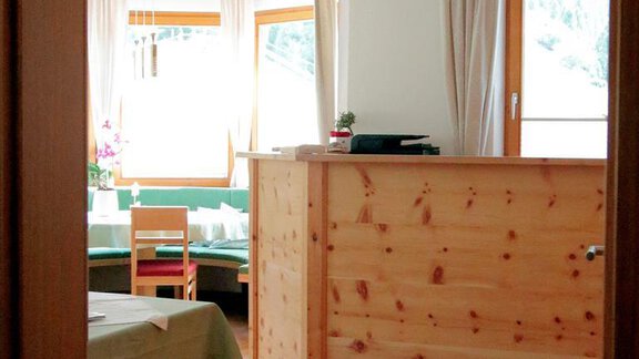 A bright room with wooden furniture and large windows. The reception desk is made of wood and the atmosphere feels inviting. - Gästehaus Soldanella - Vent