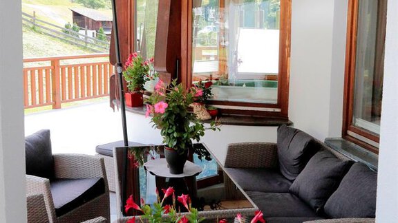 A cozy terrace with comfortable furniture and colorful flowers. A sunshade provides shade and invites relaxation. - Gästehaus Soldanella - Vent