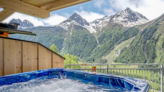 A hot tub on a terrace overlooking impressive mountains. The surroundings are green and offer a calm, relaxing atmosphere. - Hotel Burgstein alpin & lifestyle - Längenfeld
