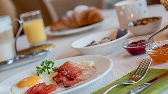 A delicious breakfast with scrambled eggs, ham, and fresh tomatoes. There are various jams and a glass of freshly squeezed juice. - Hotel-Garni Pirchhütt - Obergurgl 