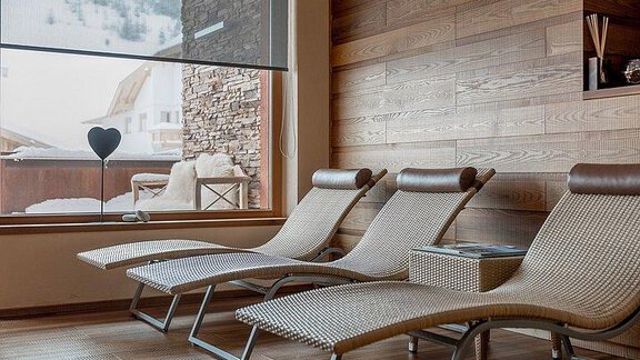 A tranquil wellness area with three loungers and a large window. Outside, a snowy landscape can be seen. - Hotel-Garni Pirchhütt - Obergurgl 
