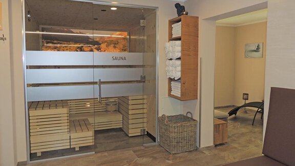 A modern sauna area with a glass front and wooden benches. Towels are neatly stacked, and there is a relaxing atmosphere. - Haus Christophorus - Obergurgl 