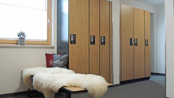 A modern changing room with wooden lockers and a cozy bench. The windows let in plenty of daylight and planted decorations create an inviting atmosphere. - Haus Christophorus - Obergurgl 