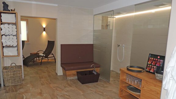 A modern wellness area with a comfortable seating area and a shower. Towels and a shelf with glasses are visible. - Haus Christophorus - Obergurgl 