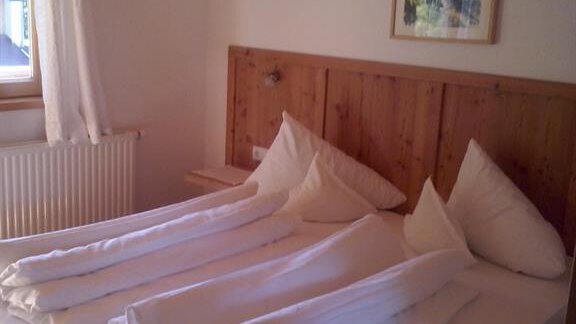 A cozy bedroom with a double bed and wooden furniture. Large windows provide plenty of daylight. - Pension Angern - Obergurgl 