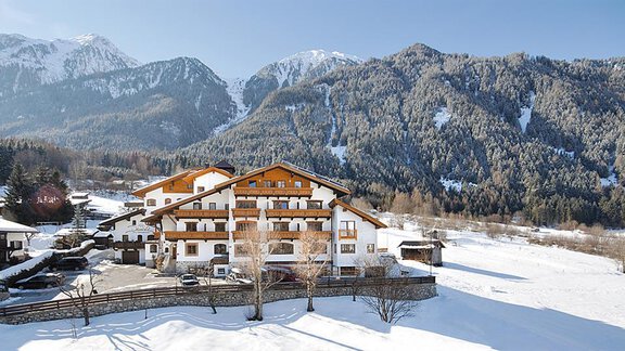 A picturesque mountain hotel surrounded by snow-covered mountains. The sunny landscape invites relaxation and enjoyment. - Aktiv Panoramahotel Daniel - Sautens