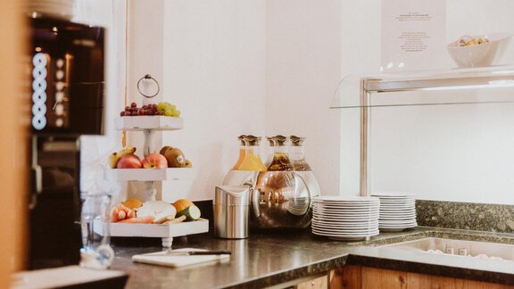 A modern coffee bar with fresh fruit and drinks on a table. The room is bright and invitingly designed. - Apart Hotel Garni Alt Kaisers - Sölden