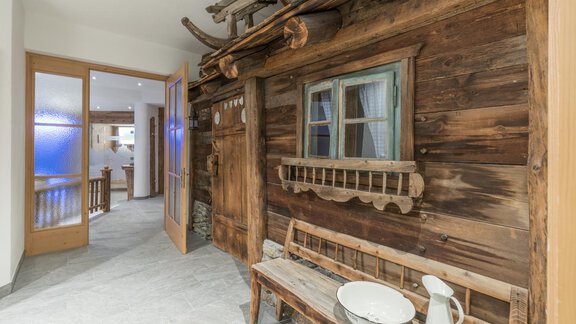 A rustic room with a wooden wall and a small window. A bench and a jug are in the foreground. - Apart Hotel Garni Alt Kaisers - Sölden