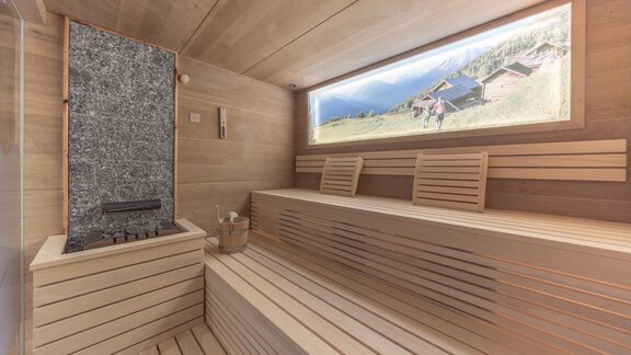 A modern-designed wellness area with a wooden sauna and comfortable loungers. Large windows offer a view of the mountain landscape. - Apart Hotel Garni Alt Kaisers - Sölden