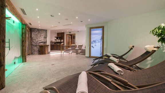 An elegant wellness area with comfortable loungers and soft lighting. In the background, there is a bar and a window that offers a view of the surroundings. - Apart Hotel Garni Alt Kaisers - Sölden