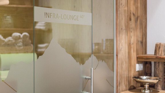 A modern glass door with the inscription "INFRA:LOUNGE" and a mountain silhouette. The background features a cozy, wood-paneled setting. - Apart Hotel Garni Alt Kaisers - Sölden