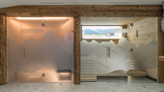 A modern wellness area with large glass walls and wooden accents. The walls are adorned with a stylized mountain motif. - Apart Hotel Garni Alt Kaisers - Sölden