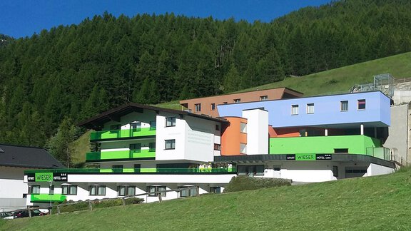 A modern building with colorful facades, surrounded by green meadows and trees. The architecture is striking and designed to be welcoming. - Apart Hotel Garni Wieser - Sölden