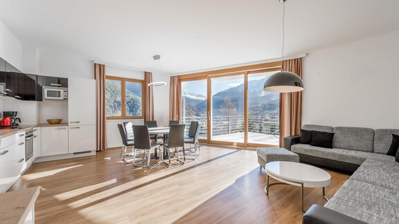 A modern apartment with large windows and a view of the mountains. The living area is bright and welcoming, with a dining area and a cozy sofa corner. - Apart Hotel Garni Wieser - Sölden