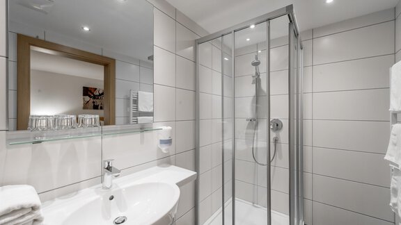 A modern bathroom with a glass shower cabin. The sink area is clean and well organized. - Apart Hotel Garni Wieser - Sölden