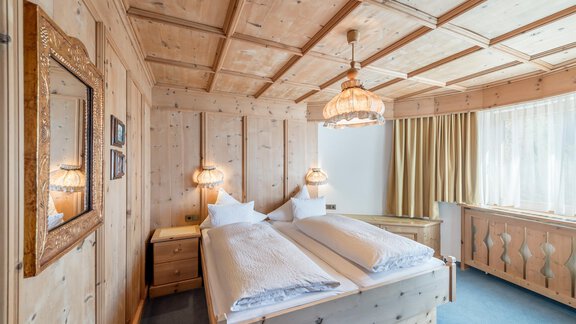 A cozy bedroom with wooden ceilings and two beds. There is a mirror and warm lighting that creates an inviting atmosphere. - Apart Hotel Garni Wieser - Sölden
