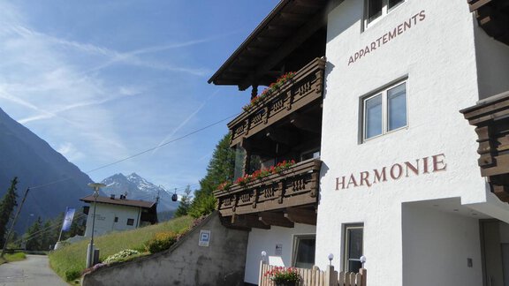 A cozy apartment house named "Harmonie" in a picturesque mountain landscape. The surroundings are green, and the mountains are visible in the background. - Appartement Harmonie - Sölden