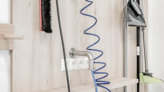 A wall with various cleaning tools and equipment. Visible are brooms, brushes, and a hose, neatly hung up. - Appartementhaus Kathrin - Sölden