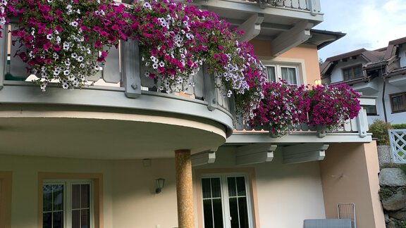 A cozy building with blooming balconies and a well-kept garden. Garden furniture is positioned outside the door for relaxation. - Appt. Ideal - Sölden