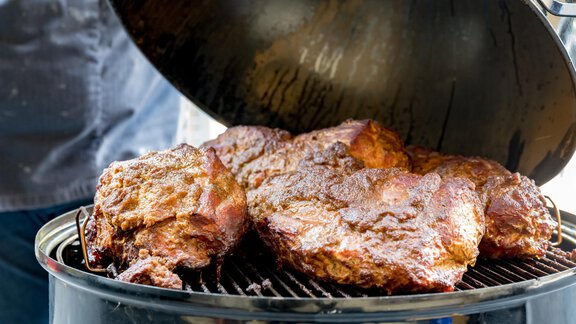 Ein Grill mit saftigem, gegrilltem Fleisch liegt unter einem offenen Deckel. Die goldbraune Kruste verspricht einen köstlichen Geschmack. - Bäckelar Wirt - Sölden