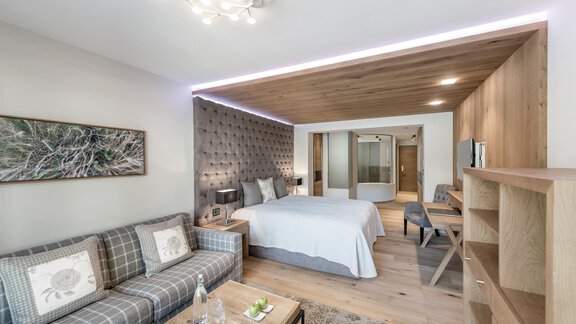Ein modernes Hotelzimmer mit einem großen Bett und einem komfortablen Sofa. Die Einrichtung ist stilvoll und gut beleuchtet. - Das Central - Alpine . Luxury . Life - Sölden | © Rudi Wyhlidal