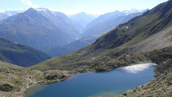 A picturesque mountain lake surrounded by high mountains. The clear sky is reflected in the water. - Ferienhof Paulelas - Sölden