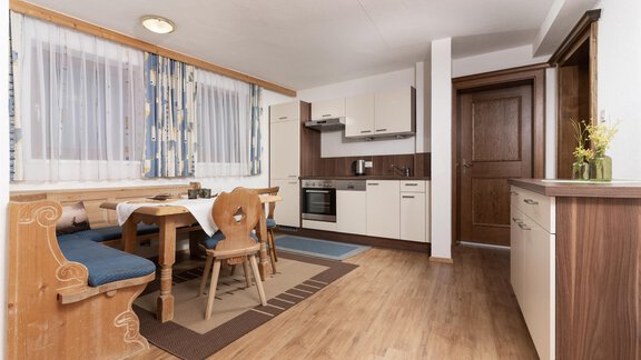 A modern kitchen with a wooden dining table and a cozy bench. Large windows let in plenty of light and create an inviting atmosphere. - Gurgler Hof - Sölden