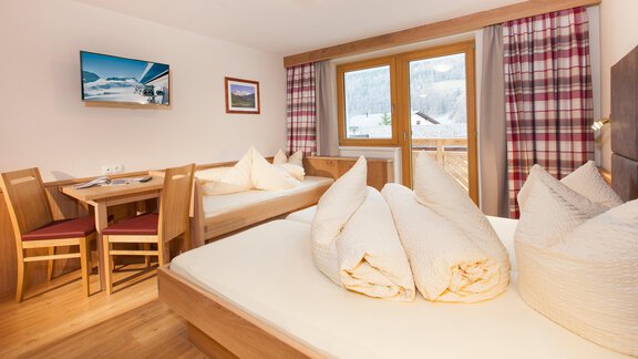 A cozy room with two beds and a dining table. Large windows with a view of the mountains and a warm, inviting atmosphere. - Haus Bergblick - Sölden