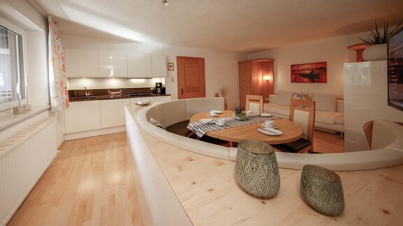 A modern kitchen with a round dining area and wooden floor. The decor is bright and inviting. - Haus Ingrid - Sölden