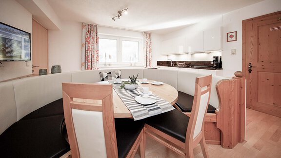 A modern kitchen with a round dining table and comfortable seating. Bright colors and plenty of natural light create an inviting atmosphere. - Haus Ingrid - Sölden