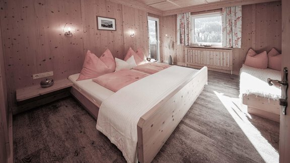 A cozy bedroom with wood paneling and two beds. The decor is bright and inviting, with beautiful curtains and cushions in soft colors. - Haus Ingrid - Sölden