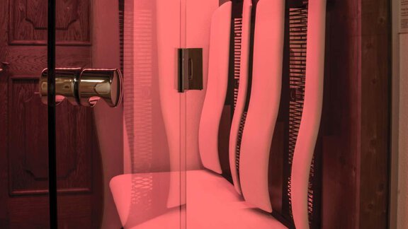 A modern infrared sauna cabin with soft red light. The walls are equipped with comfortable seating areas. - Haus Tanja - Sölden