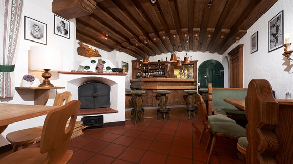 A cozy restaurant with a wooden ceiling and traditional decor.  
Wooden tables and chairs create an inviting atmosphere. - Hotel am Hof - Sölden