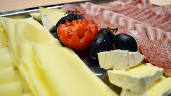 A platter with various types of cheese, sausage, olives, and a tomato. The colors and textures of the food provide an appealing presentation. - Pension "Zur alten Mühle" - Sölden | © Carmen Waldhart