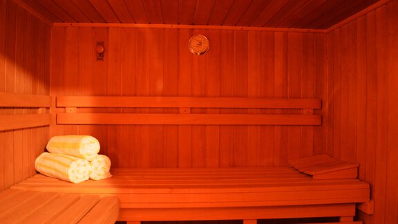 A Finnish sauna with wooden paneling and several benches. Folded towels are lying on one of the benches. - Pension "Zur alten Mühle" - Sölden | © Carmen Waldhart