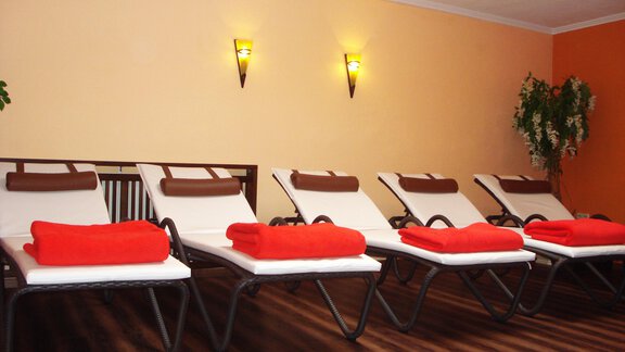Five loungers with red towels in an inviting room. Soft lighting and green plants create a relaxed atmosphere. - Pension "Zur alten Mühle" - Sölden | © Carmen Waldhart
